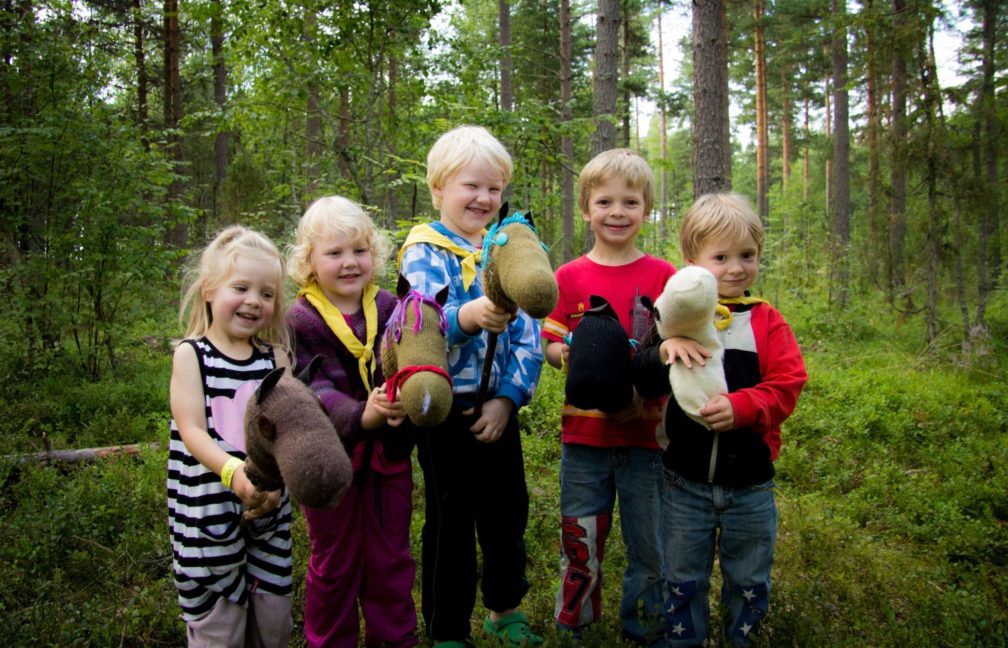 Lapsia keppihevosten kanssa metsässä.
