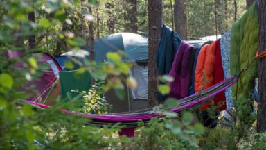 teltta, riippumatto, ja kuivumassa riokkuvia makuupusseja metsässä